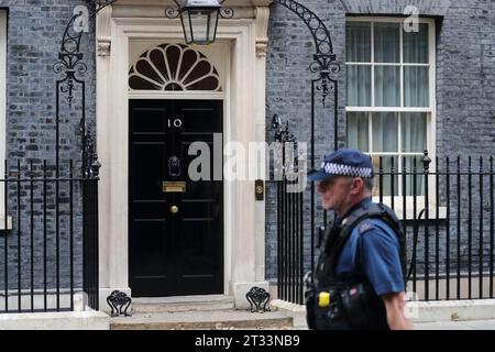 Un agente di polizia armato passa davanti all'entrata al numero 10 di Downing Street, Londra, Regno Unito Foto Stock