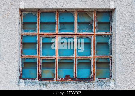 Vecchie finestre della griglia del magazzino di fabbrica con vetro rotto come sfondo industriale Foto Stock