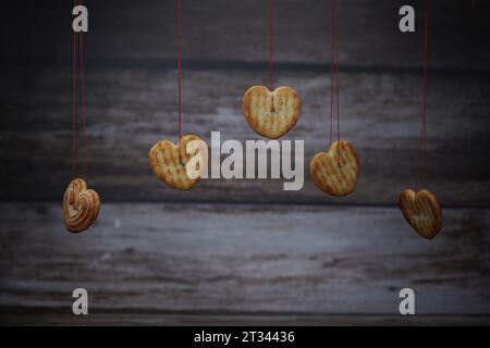 Alcuni biscotti a forma d'amore sono appesi al cordoncino Foto Stock