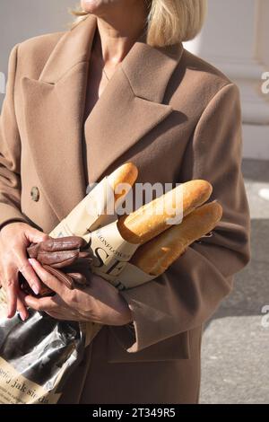 Le mani femminili trattengono i pani francesi avvolti in carta artigianale Foto Stock