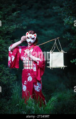 donna con lanterna di carta e maschera nella foresta Foto Stock