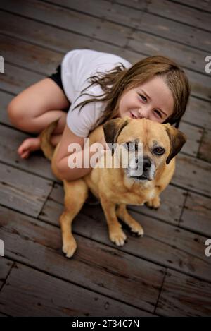 Una bambina felice che accarezza fuori il cane puggle marrone Foto Stock