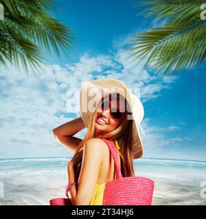 Giovane donna attraente con occhiali da sole e cappello di paglia che cammina sulla spiaggia tropicale, vacanze estive e concetto di viaggio Foto Stock