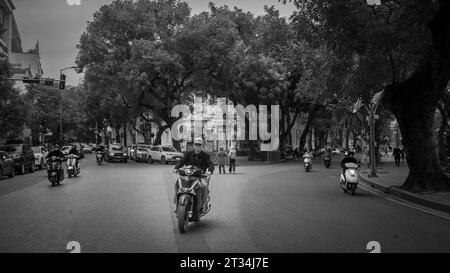 Un uomo vietnamita guida la sua motocicletta lungo le Thai per stressarsi in una giornata invernale al centro di Hanoi, in Vietnam. Foto Stock