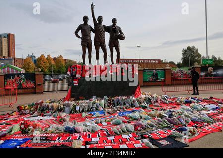 I fiori posati alla statua della Trinity mentre i fan rendono omaggio al defunto Sir Bobby Charlton fuori Old Trafford, Manchester, Regno Unito, 23 ottobre 2023 (foto di Conor Molloy/News Images) Foto Stock