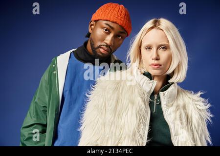 coppia interrazziale in moderno abbigliamento invernale, giovane donna con giacca in pelliccia sintetica e uomo afro-americano Foto Stock