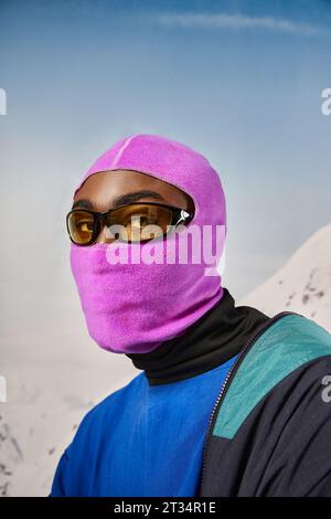 giovane afroamericano con balaclava rosa e occhiali da sole che guardano la macchina fotografica, concetto invernale Foto Stock