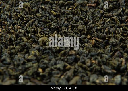 Carta da parati Black Dry Tea. Mescolare le foglie di tè nero e verde che ruotano sul piano girevole. Primo piano, Macro. Vista dall'alto. Trama. Full frame. Copia spazio. Tè secco i Foto Stock