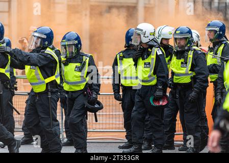 La polizia antisommossa arriva a una manifestazione di protesta per l'arresto di Tommy Robinson, con fumosità di manifestanti che si riversano per strada a Whitehall, Londra, Regno Unito Foto Stock