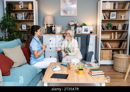Felice giovane infermiera donna fornire assistenza assistenza assistenza medica aiutare a sostenere sorridente vecchia nonna alla visita medica di cura domiciliare, signora curatrice medico dare empatia encou Foto Stock