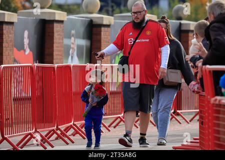 Una famiglia lascia alcuni fiori in omaggio al defunto Sir Bobby Charlton fuori Old Trafford, Manchester, Regno Unito, 23 ottobre 2023 (foto di Conor Molloy/News Images) Foto Stock