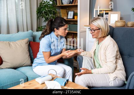 Felice giovane infermiera donna fornire assistenza assistenza assistenza medica aiutare a sostenere sorridente vecchia nonna alla visita medica di cura domiciliare, signora curatrice medico dare empatia encou Foto Stock