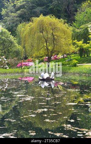 Scultura galleggiante e albero del Giglio riflesso nel lago Magnolia presso l'Himalayan Garden & Sculpture Park vicino a Ripon, North Yorkshire, Inghilterra, Regno Unito. Foto Stock