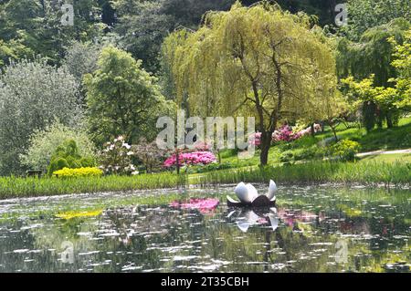 Scultura galleggiante e albero del Giglio riflesso nel lago Magnolia presso l'Himalayan Garden & Sculpture Park vicino a Ripon, North Yorkshire, Inghilterra, Regno Unito. Foto Stock