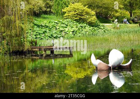 Scultura galleggiante di Lily e molo di legno riflesso nel lago Magnolia presso l'Himalayan Garden & Sculpture Park vicino a Ripon, North Yorkshire, Inghilterra, Regno Unito Foto Stock