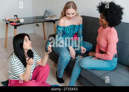 Donna con specchio a mano e amici seduti sul divano Foto Stock