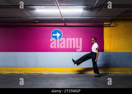 Giovane donna d'affari che cammina davanti al muro Foto Stock
