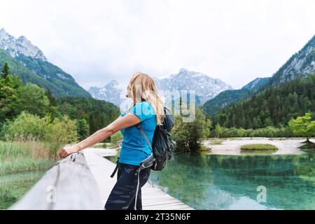 Escursionista che si gode la vista delle montagne dal molo sul fiume Foto Stock