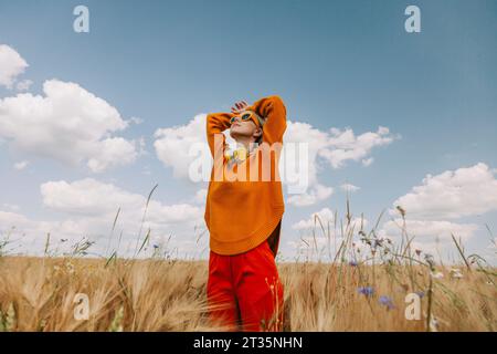 Donna con la testa in mano in piedi in un campo di grano Foto Stock