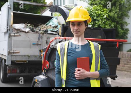 Operaio con collare blu che tiene il diario vicino al dumper Foto Stock