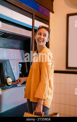 Donna sorridente che preleva denaro dal bancomat Foto Stock