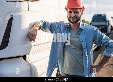 Camionista sorridente in piedi accanto al camioncino Foto Stock