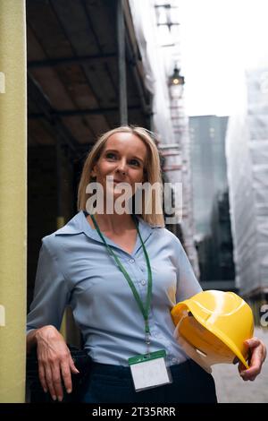 Ingegnere premuroso che tiene duro cappello in cantiere Foto Stock