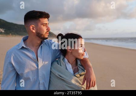 Fidanzato con la fidanzata in spiaggia al tramonto Foto Stock