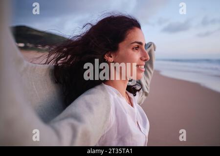 Donna sorridente che trascorre il tempo libero in spiaggia Foto Stock
