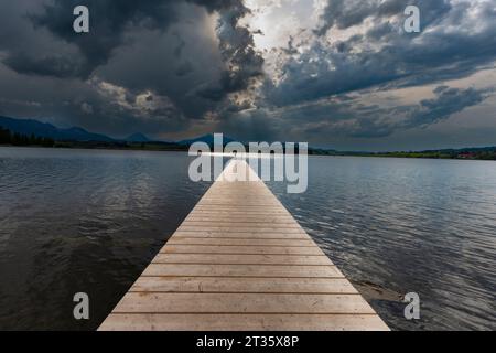 Germania, Baviera, Hopfen am SEE, nuvole di tempesta sul molo vuoto sul lago Hopfensee Foto Stock