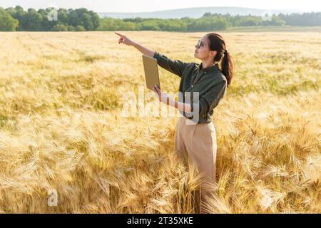 Agronomo che gestisce e parla durante una videochiamata tramite un tablet PC sul campo Foto Stock