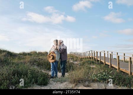 Coppia anziana in piedi tra le piante sotto il cielo nuvoloso nelle giornate di sole Foto Stock