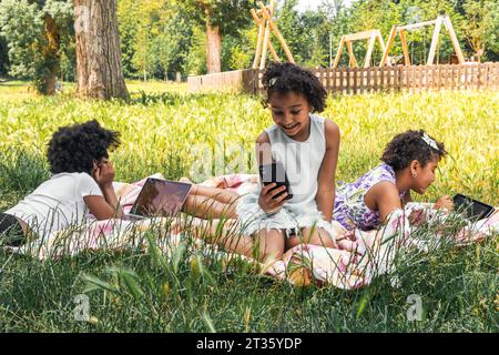 Sorelle felici che trascorrono del tempo con la tecnologia wireless in giardino Foto Stock