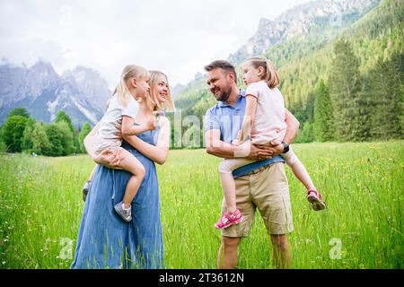 Padre e madre in piedi con le figlie di fronte alle montagne Foto Stock