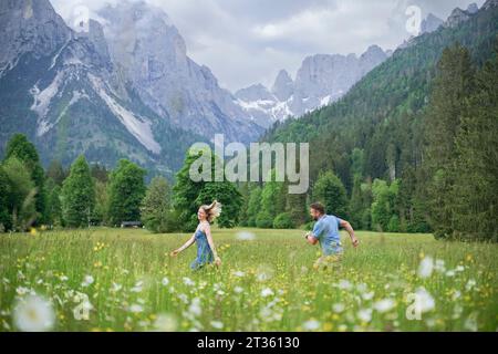 Uomo e donna che corrono di fronte alle montagne Foto Stock
