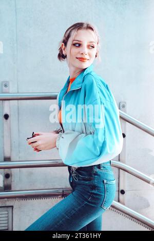 Donna sorridente in piedi di fronte alla ringhiera Foto Stock