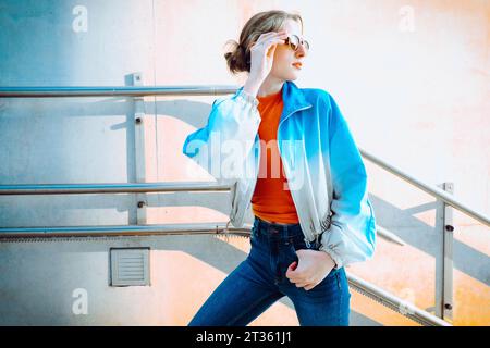 Donna alla moda in piedi di fronte alla ringhiera Foto Stock