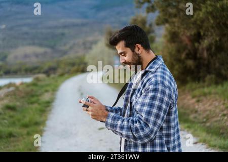 Uomo sorridente che utilizza il controller dei droni sul sentiero Foto Stock