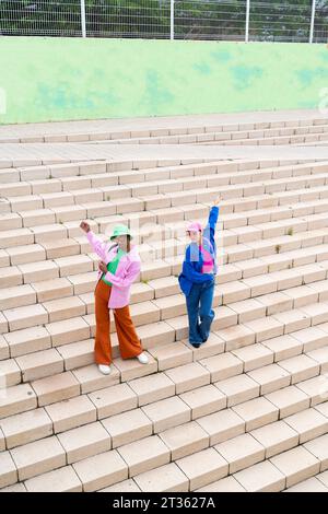 Persona non binaria che balla con donna sulle scale Foto Stock