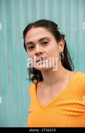 Donna con adesivi sotto gli occhi davanti alla porta blu Foto Stock