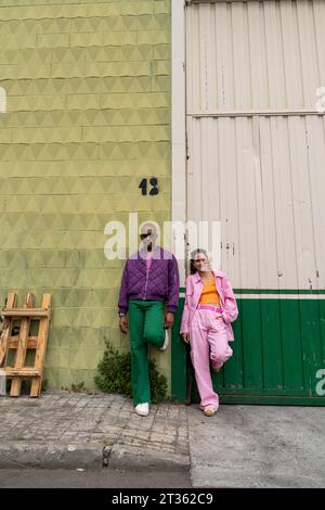 Coppia alla moda che si appoggiano insieme sul muro del sentiero Foto Stock