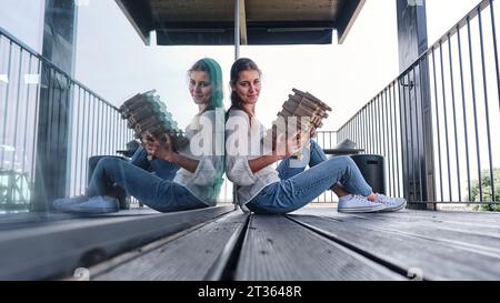 Ritratto di una bella donna bionda seduta sul balcone con scatola di cartone in mano Foto Stock