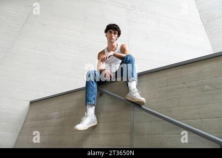 Giovane uomo seduto sulla parete Foto Stock