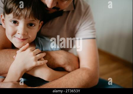 Padre che abbraccia il figlio a casa Foto Stock