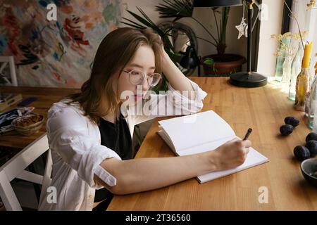 L'artista scrive su un blocco note alla scrivania Foto Stock