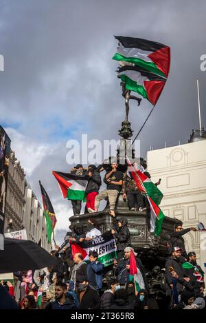 I manifestanti sventolano bandiere in cima alla statua di Eros a Piccadilly Circus, protesta pro-palestinese nel centro di Londra il 21/10/2023, Inghilterra, Regno Unito Foto Stock