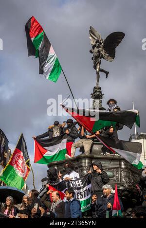 I manifestanti sventolano bandiere in cima alla statua di Eros a Piccadilly Circus, protesta pro-palestinese nel centro di Londra il 21/10/2023, Inghilterra, Regno Unito Foto Stock