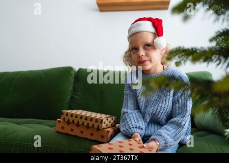 Ragazza premurosa seduta con regali di Natale a casa Foto Stock