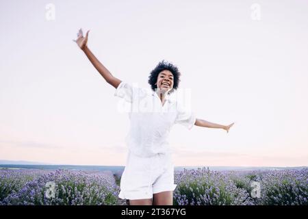 Donna sorridente che si diverte nel campo di lavanda Foto Stock