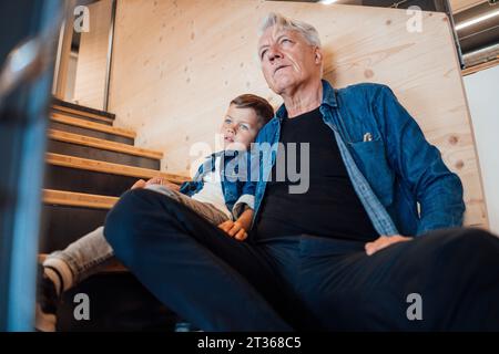 Nipote e nonno seduti sulle scale a casa Foto Stock
